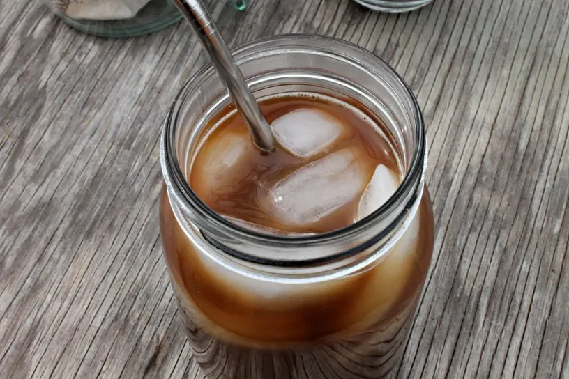 The original photo: iced cold brew in a glass jar with a metal straw, on a weathered wooden table