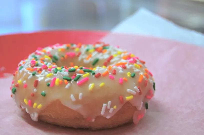 The original photo: a glazed rainbow sprinkle donut on pink paper